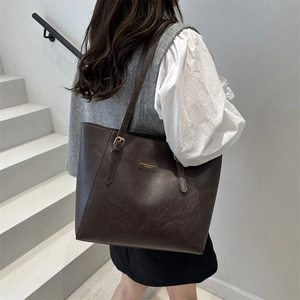 Grand sac cabas marron foncé minimaliste porté par un mannequin de profil en extérieur