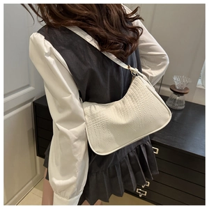 Detail of white crocodile pattern hobo bag with gold buckle on a model's shoulder