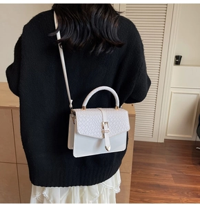 Détail du sac à main blanc à texture tressée avec boucles dorées et cuir gaufré croco