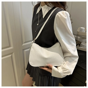 Detail of white crocodile pattern shoulder bag with adjustable strap on model