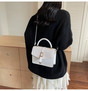 Sac bandoulière blanc à texture tissée et détails dorés, accessoire de mode élégant