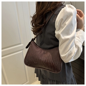 Detailed close-up of dark brown crocodile texture on a minimalist shoulder baguette bag