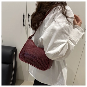 Woman wearing a vintage burgundy faux crocodile leather crescent-shaped underarm bag