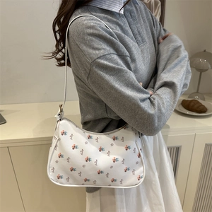 Floral print shoulder bag with zipper closure shown in a minimalist aesthetic setting