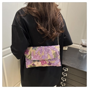 Detail of floral sequin embroidery and gold chain on straw envelope clutch bag