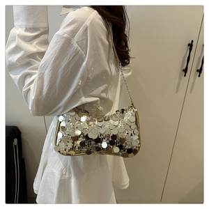 Detail of silver sequin shoulder bag with gold trim and chain strap on a model