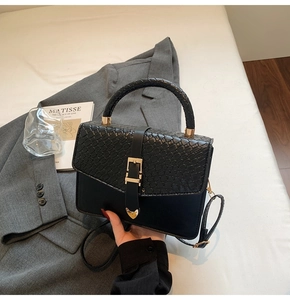 Détail du sac bandoulière noir avec texture crocodile et boucle en métal doré en cœur