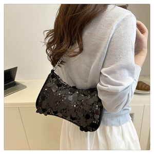 Shoulder bag with black sequins and silver chain strap shown in a lifestyle cafe setting
