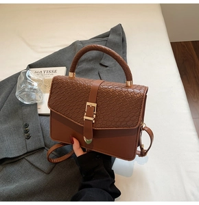 Détail du sac à main marron foncé avec rabat texturé et boucle cœur dorée élégante