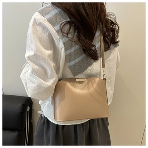Detail der minimalistischen beigen Beuteltasche mit Goldrand und schmalem Schultergurt