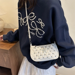 Petit sac bandoulière blanc matelassé avec étoile argentée porté par un mannequin chic