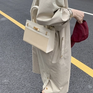 Chic beige canvas and leather Kelly style handbag on urban street background