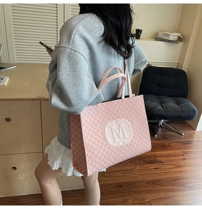 Detailed view of pink tote bag featuring all-over M pattern and embossed circular logo