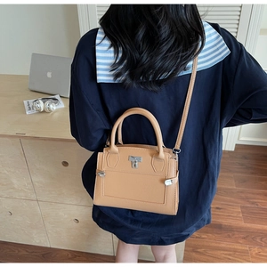Detail of caramel lychee grain handbag with silver lock shown in lifestyle office setting