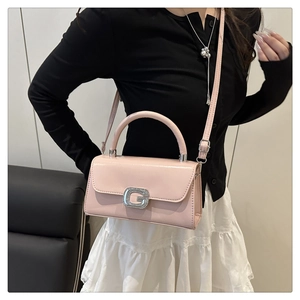 Detail of light pink square bag with sparkling G-buckle worn on person's shoulder
