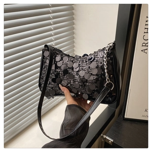 Detailed macro view of large black sequins and silver chain on a stylish shoulder bag