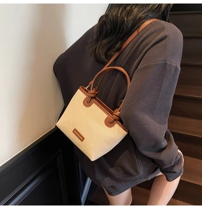 Detail of woven fabric handbag with leather handles and Fashion & Bags logo on a staircase