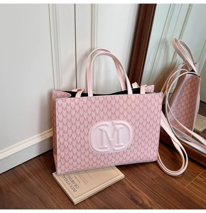 Close-up of pink tote bag with M letter print and embossed oval logo detail
