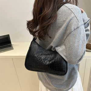Minimalist black crocodile pattern underarm bag shown in a stylish shoulder carrying view