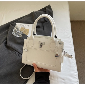 Detail of white lychee-grain faux leather handbag with silver metal padlock and top handle