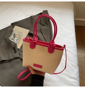 Detail of straw woven tote bag featuring vibrant pink leather trim and dual handles