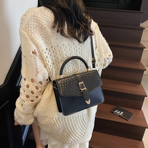 Sac bandoulière noir tendance avec détail serpent et boucle dorée sur un mannequin