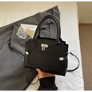 Close-up of black lychee grain leather handbag with silver lock and hardware details