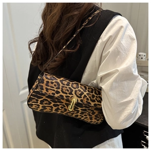 Macro view of leopard print baguette bag with golden metal buckle on model's shoulder