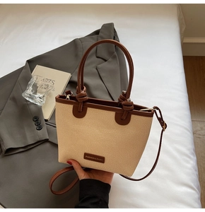 Close-up of woven straw bucket bag with leather handles and a fashion metal brand plate