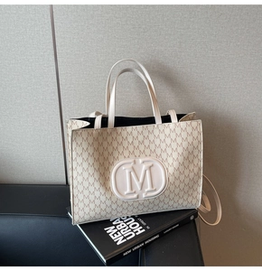 Detailed close-up of a beige tote bag featuring M-letter pattern on textured leather
