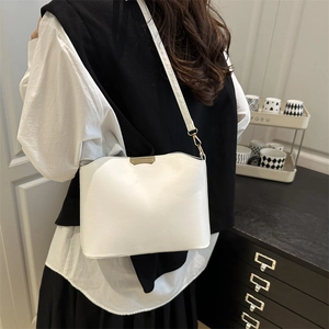 Minimalist white shoulder bag with wave edge and gold metal clasp worn by a model
