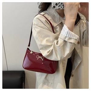 Detail of red patent leather baguette bag featuring a stylish golden bow metal buckle
