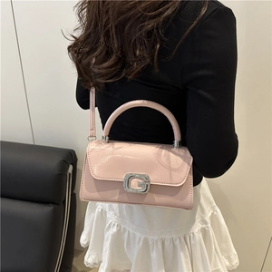 Elegante borsa a mano in pelle verniciata rosa chiaro con fibbia G su una modella