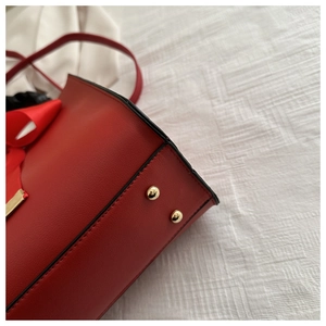 Gros plan d'un sac à main rouge montrant la texture du cuir et des rivets dorés chics