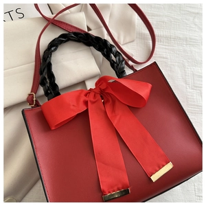 Détail du sac à main rouge avec grand nœud en satin et poignées en tissu tressé