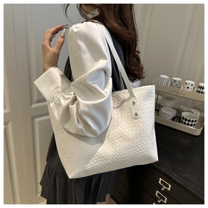 Detail of white woven leather tote bag featuring gold rivets and elegant texture