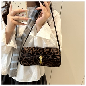 Detail of leopard print baguette bag featuring an oval gold metal buckle and slim strap