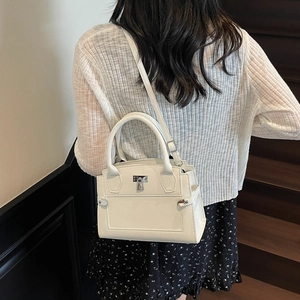 Minimalist off-white pebbled leather handbag with silver twist lock and crossbody strap