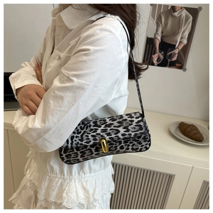 Close-up of leopard print baguette bag with gold twist lock on a minimalist desk