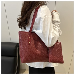 Detail of burgundy textured tote bag with small pouch shown on model shoulder