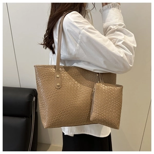 Detail of khaki woven tote bag showing the matching inner pouch and leather texture