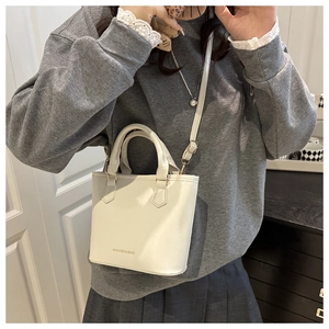 Close-up of white mini tote bag with lychee texture and golden metal hardware details