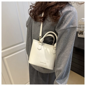 White minimalist bucket bag with Fashion & Bags gold lettering and slim shoulder strap