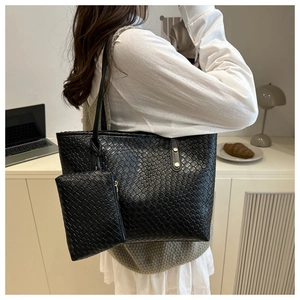 Detail of black woven leather tote bag with matching small inner pouch and gold rivets