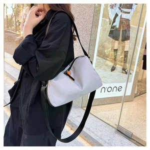 Detail of light gray nylon crossbody messenger bag with orange zipper pull accent