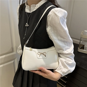 White glossy patent leather baguette bag with golden bow and flower pendant detail
