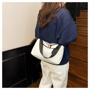 Detail of white nylon messenger bag with contrast orange zippers and patterned strap