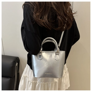 Detail of silver metallic bucket bag with FASHION & BAGS text and slim shoulder strap