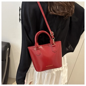 Detail of red patent leather bucket bag with gold Fashion & Bags lettering print