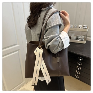 Detail of dark brown leather tote bag featuring white contrast stitching and a long strap
